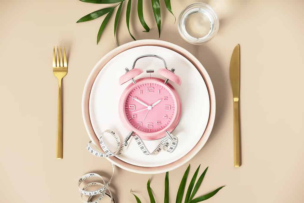 Composition with cutlery, plate, measuring tape, water and alarm clock on color background, flat lay, top view